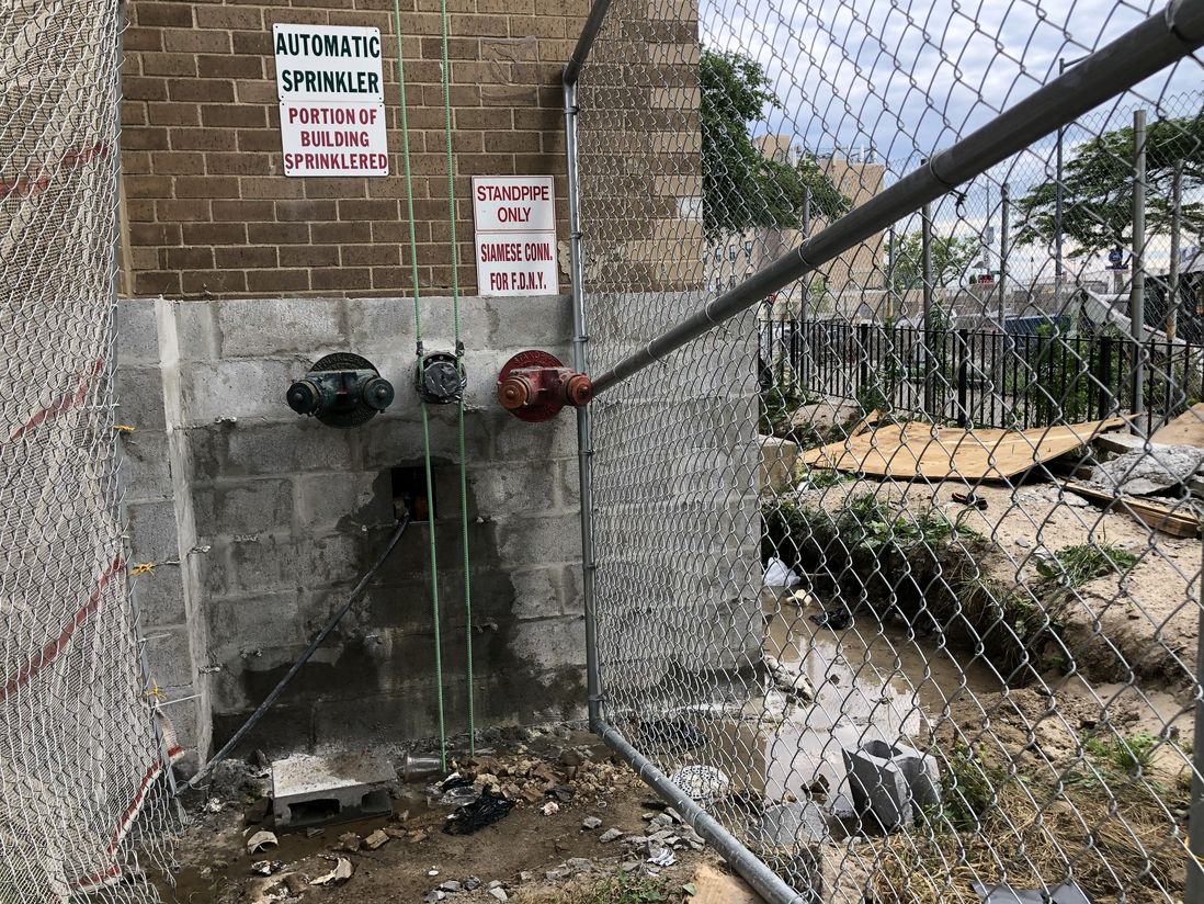 Water leaks out of a hole in the wall at 2977 West 33rd St in Coney Island, creating a running stream around the base of the building.